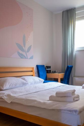 a bedroom with a bed and two blue chairs at Mint Hotel in Prizren
