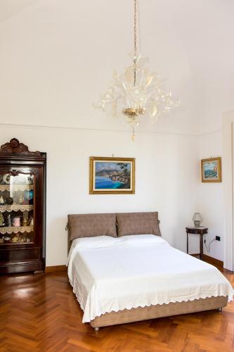 a bedroom with a white bed and a chandelier at Capitano Nino Guest House in Meta