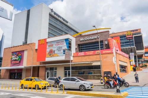 a street scene with cars and people in front of a mall at Zentrico Boutique in Pereira