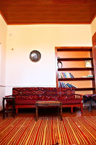a red bench in a room with a book shelf at Odyssey Guest House in Bergama