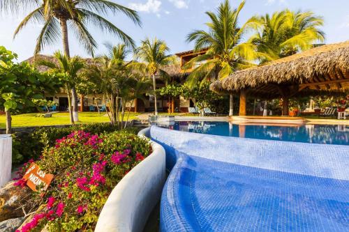 a swimming pool at a resort with palm trees and flowers at Casa Manzanillo Boutique Hotel in Troncones