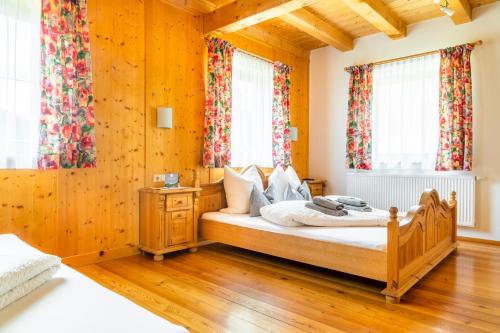 a bedroom with a bed with wooden floors and windows at Öko-Appartements Fallhaus in Forstau