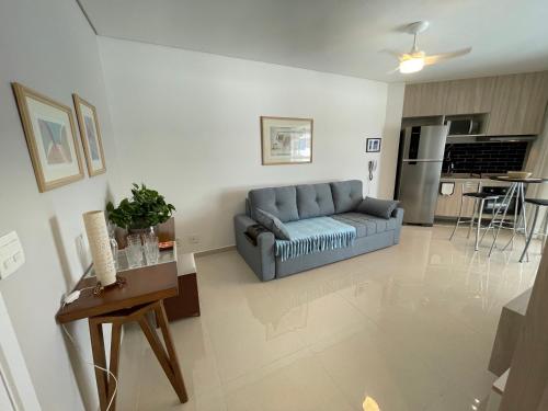a living room with a blue couch and a kitchen at Estanconfor Santos Vista Mar 4 AC Garagem sacada fechada in Santos