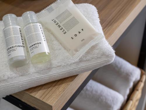 two bottles of essential oils and towels on a shelf at Lexum by Bernalo Hotels in Medellín