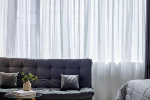 a couch sitting in front of a window with white curtains at Lexum by Bernalo Hotels in Medellín