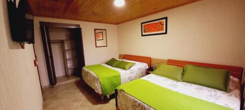 1 dormitorio con 2 camas con sábanas verdes y TV en Hoteles Bogotá Inn Colonial, en Bogotá