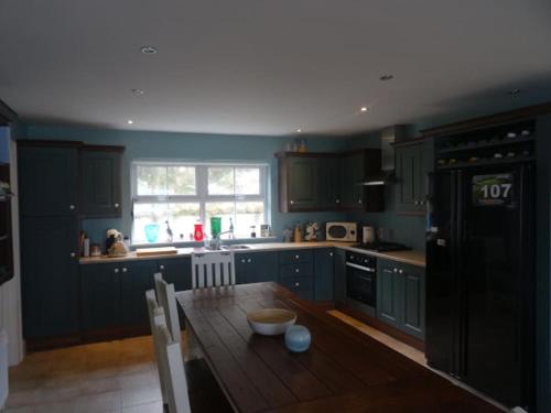 uma cozinha com armários azuis e uma mesa de madeira em Everest Lodge Guest House em Dunfanaghy