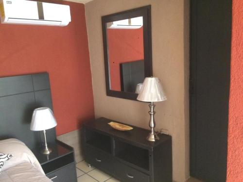 een slaapkamer met een bed, een spiegel en een lamp bij Villa Paraiso in Emiliano Zapata