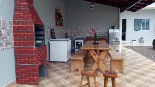 Una cocina con una mesa de madera y dos taburetes. en Casa nova com piscina próxima a praia e menos de 3km do centro de Ubatuba, en Ubatuba