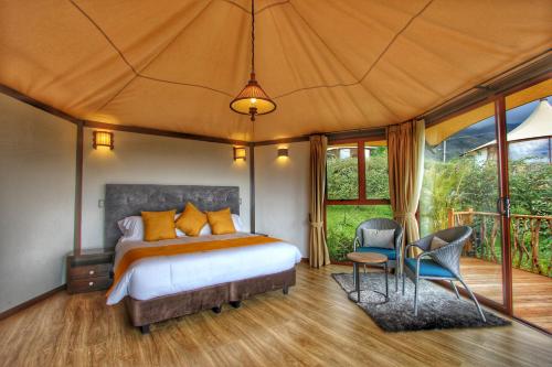 a bedroom with a bed and chairs in a tent at GENKI LUXURY GLAMPING in Villa de Leyva