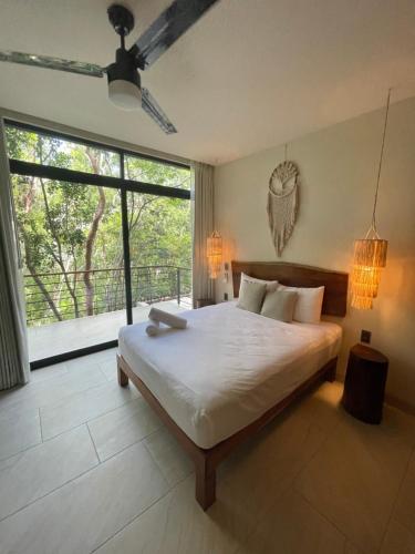 a bedroom with a large bed and a large window at Jungle View 2bed 2bath Condo/ Wi-Fi/ Pool/ Gym in Tulum