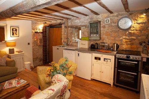 cocina y sala de estar con reloj en la pared en Popfosters Barn, en Weston Subedge