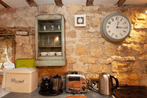 a clock on a stone wall above a kitchen counter at Popfosters Barn in Weston Subedge