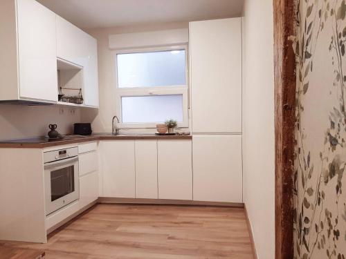 una cocina con armarios blancos y una ventana en Precioso apartamento en el centro de Santander, en Santander