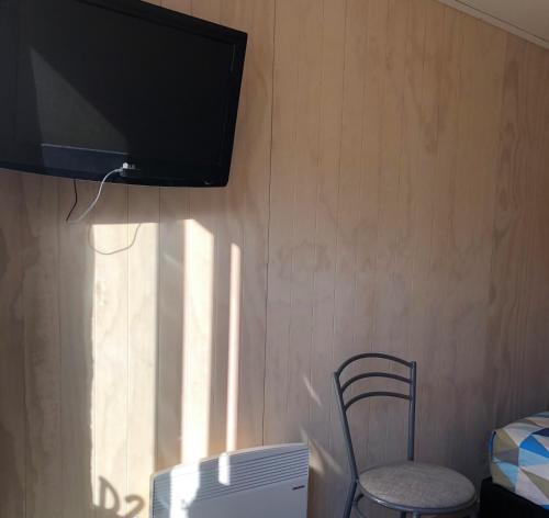 a room with a chair and a television on a wall at Lakes Edge Lodge in Lake Tekapo