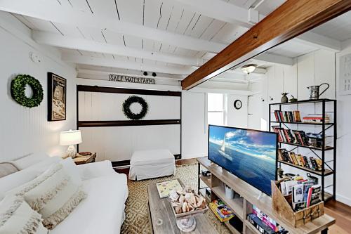 a living room with a white couch and a flat screen tv at Bayside Gardens Grande in Boothbay Harbor