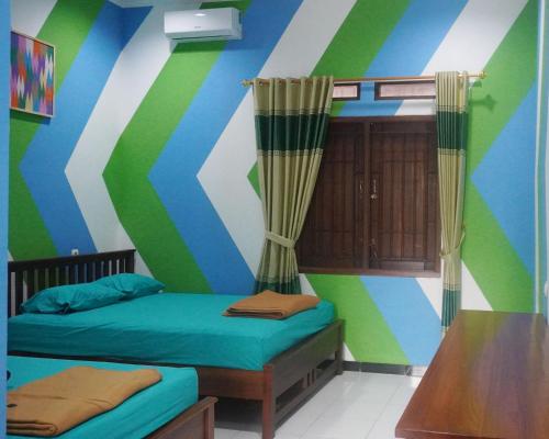 a room with two beds and a striped wall at JOGLO Greenhouse in Ngemplak