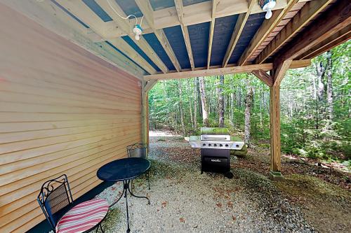 a screened in porch with a grill and a picnic table at Lazy Lumberjack Grande in Franklin