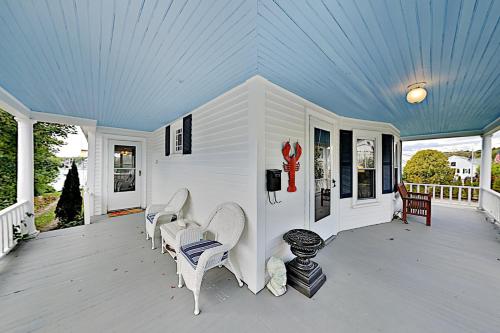 a porch with white chairs and a blue ceiling at Atlantic Gardens in Boothbay Harbor