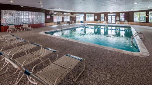 a large swimming pool with chairs in a building at Best Western Greenfield Inn in Allen Park