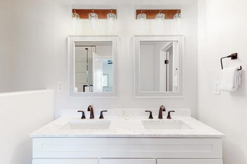a white bathroom with two sinks and two mirrors at Manassas Place in Tucson