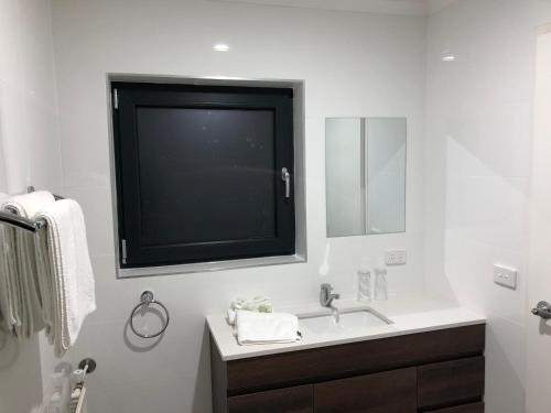 baño con lavabo y TV grande en la pared en Summit Ridge Alpine Lodge, en Falls Creek