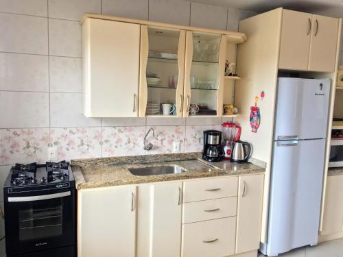 a kitchen with white cabinets and a sink and a refrigerator at Pousada Souza in Florianópolis