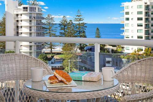 a table with a plate of food on a balcony at Pandanus Mooloolaba in Mooloolaba