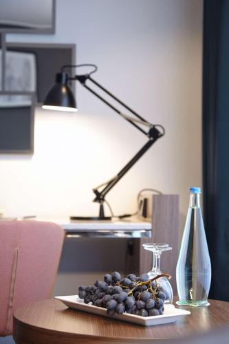 a plate of grapes on a table with a lamp at Radisson Blu Hotel Karlsruhe in Ettlingen