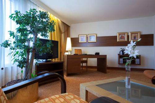 a room with a living room with a tv and a tree at Radisson Blu Hotel Karlsruhe in Ettlingen