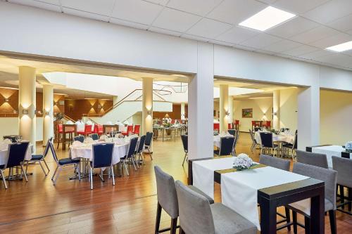 a dining room with white tables and chairs at Radisson Blu Hotel Karlsruhe in Ettlingen
