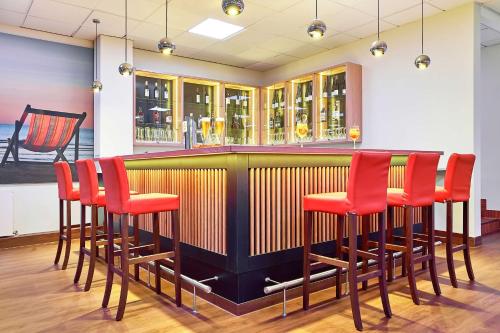 a bar with red chairs in a restaurant at Radisson Blu Hotel Karlsruhe in Ettlingen