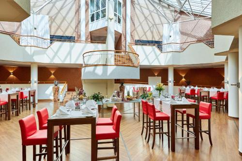 a dining room with tables and red chairs at Radisson Blu Hotel Karlsruhe in Ettlingen