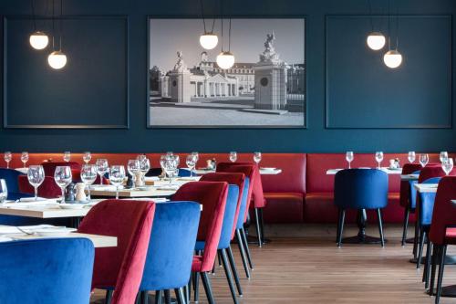 a dining room with tables and blue chairs at Radisson Blu Hotel Karlsruhe in Ettlingen