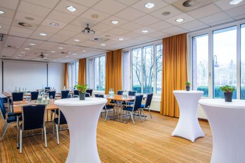 a conference room with tables and chairs and large windows at Radisson Blu Hotel Karlsruhe in Ettlingen
