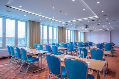 a conference room with tables and blue chairs at Radisson Blu Hotel Karlsruhe in Ettlingen
