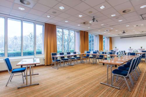a conference room with tables and chairs and windows at Radisson Blu Hotel Karlsruhe in Ettlingen