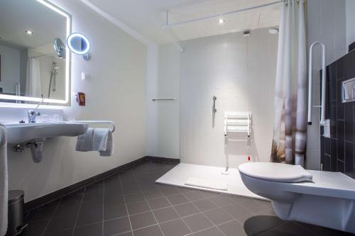 a bathroom with a toilet and a sink and a shower at Park Inn by Radisson Poznan in Poznań