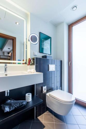a bathroom with a white toilet and a sink at Park Inn by Radisson Poznan in Poznań