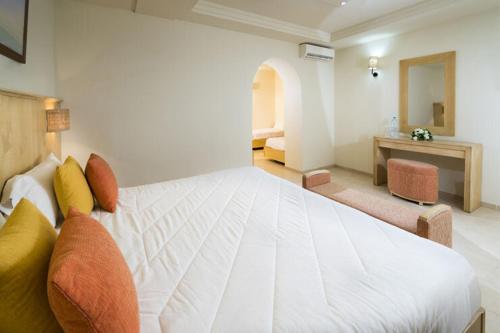 a bedroom with a large white bed and a desk at Ksar El Jerid Tozeur in Tozeur