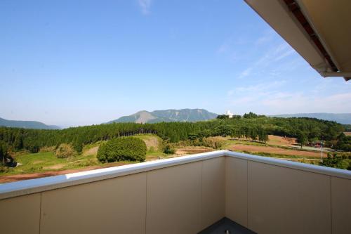 a balcony with a view of the mountains at Minamiaso Nobara Inn in Minami Aso