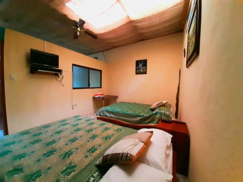 sypialnia z dwoma łóżkami i telewizorem w obiekcie Alojamiento Sumak Kawsay w mieście Puerto Ayora