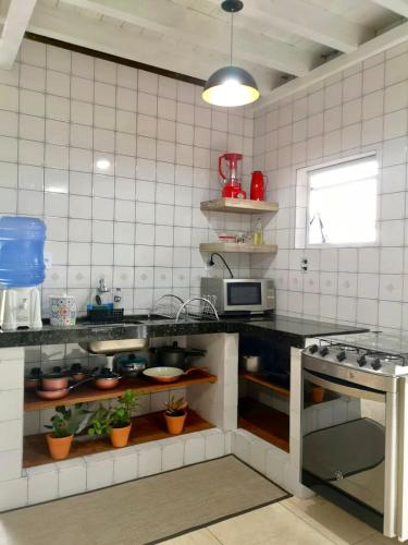 a kitchen with white tiled walls and a counter top at Double Deck - Linda vista com Jacuzzi in Palhoça