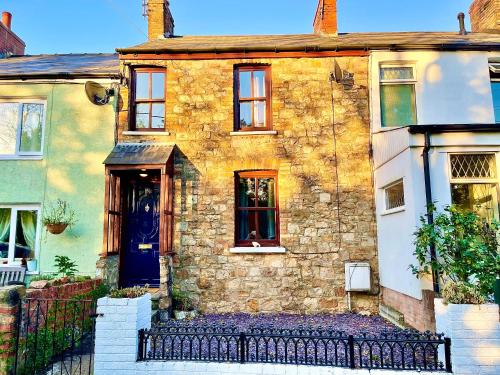 an old stone house with a blue door at Traditional cosy PET FRIENDLY cottage by the canal with Cymru Holidays in Cwm-brân