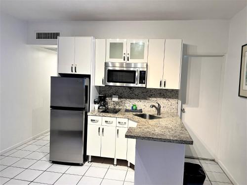 a kitchen with white cabinets and a black refrigerator at Ocean Front Units at Miami Beach in Miami Beach
