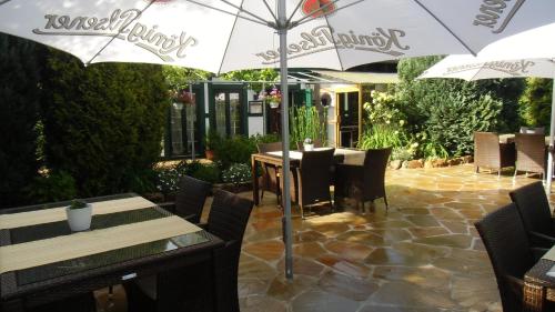 eine Terrasse mit Tischen und Stühlen und einem Sonnenschirm in der Unterkunft Landhotel-Restaurant Schwalbennest in Zierenberg