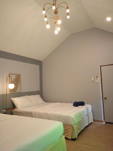 a bedroom with two beds and a chandelier at Taakradan Valley Resort ท่ากระดานวัลเล่ย์ รีสอร์ท in Ban Wang Khun Knachen