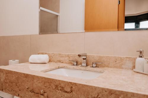 a bathroom counter with a sink and a mirror at Apartamento Le Onze Centro in Monte Verde