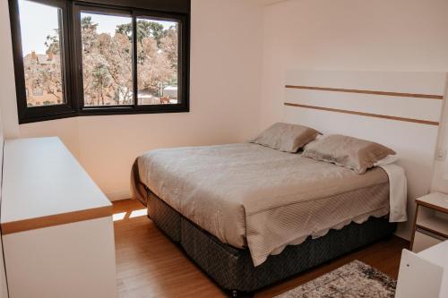 a bedroom with a bed and two windows at Apartamento Le Onze Centro in Monte Verde