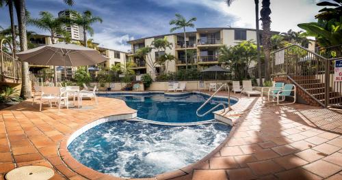 una piscina con sillas y una sombrilla y un edificio en Aussie Resort en Gold Coast